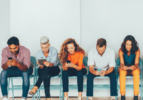 Variety of people looking at different media including books, mobile phones and tablets.